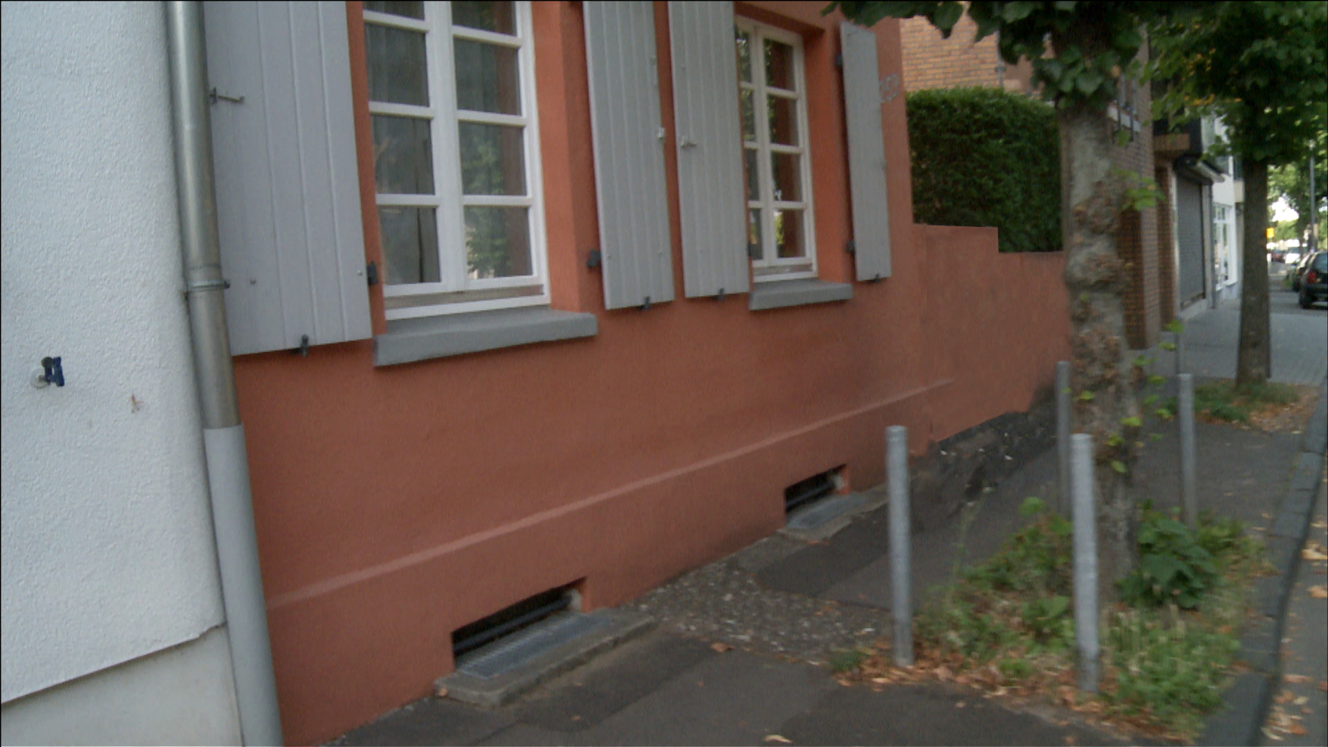 Ein Bürgersteig vor einer roten Hausfassade. Ein Radfahrer ist nicht zu sehen.