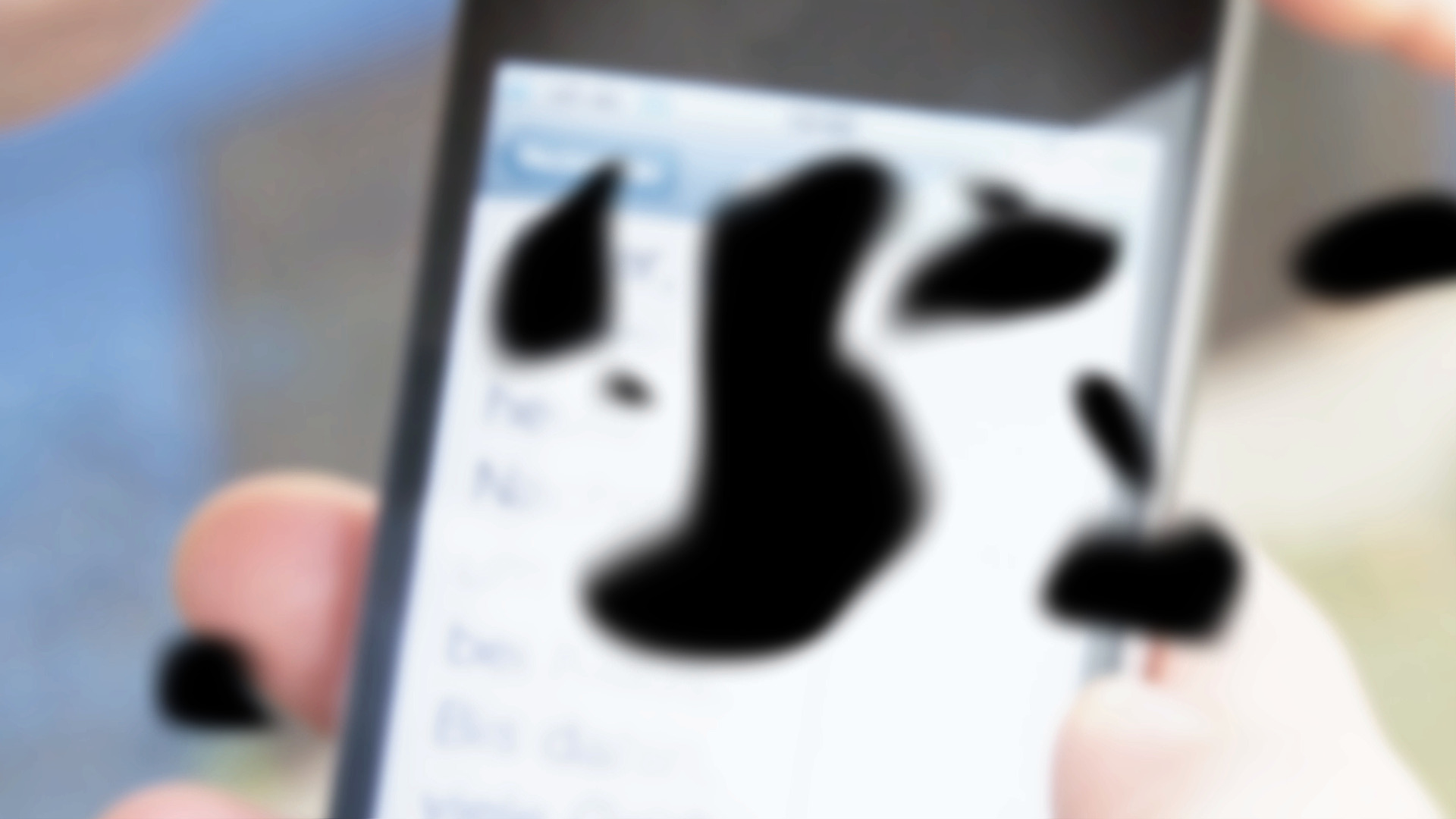 Blick auf einen Smartphone-Bildschirm, auf dem eine Textnachricht abgebildet ist. Das Bild ist unscharf, schwarze Flecken liegen über dem Sichtfeld .